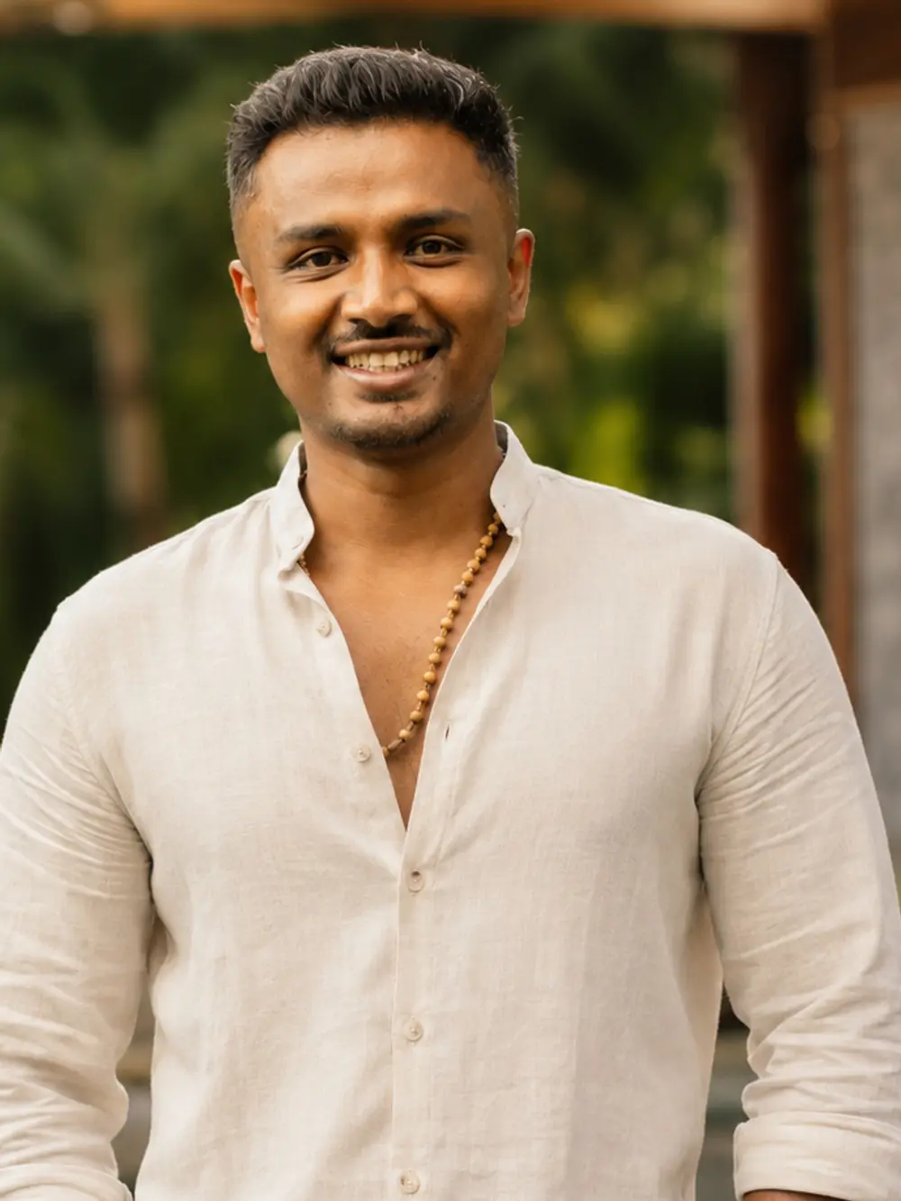 Abhiraam Gautham, standing outdoors in a cream linen shirt, looking towards the camera.