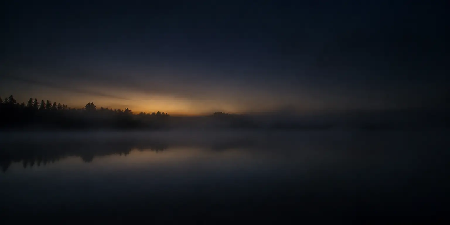Low mist over a dark lake before dawn.